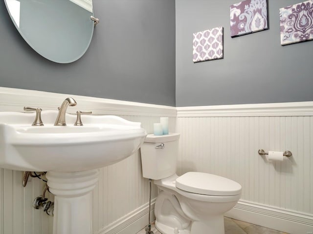 bathroom featuring toilet, a wainscoted wall, and a sink