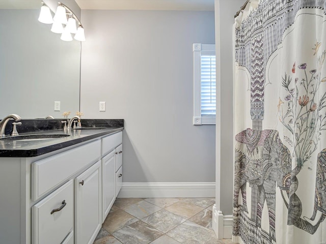 bathroom featuring baseboards, stone finish floor, and vanity