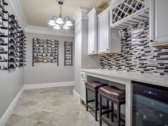 kitchen with tasteful backsplash, baseboards, light countertops, ornamental molding, and beverage cooler