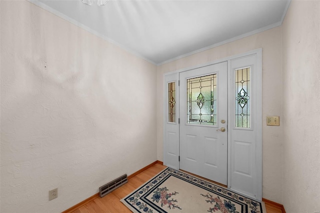 foyer with visible vents, crown molding, light wood-style flooring, and baseboards
