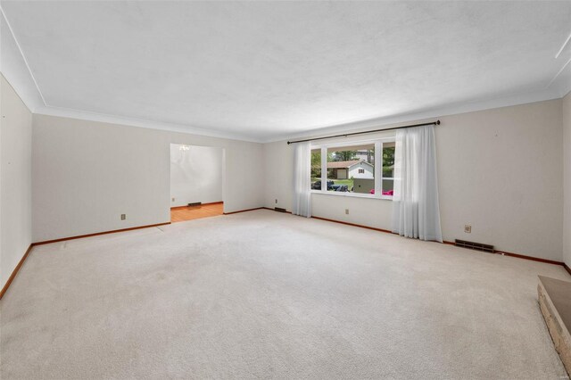 carpeted spare room featuring baseboards, visible vents, and ornamental molding