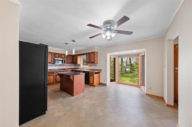 kitchen with ceiling fan, brown cabinetry, a center island, black appliances, and baseboards