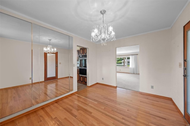 unfurnished dining area featuring a chandelier, baseboards, wood finished floors, and ornamental molding