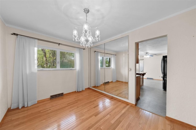 unfurnished dining area featuring ornamental molding, visible vents, light wood-style flooring, and a chandelier