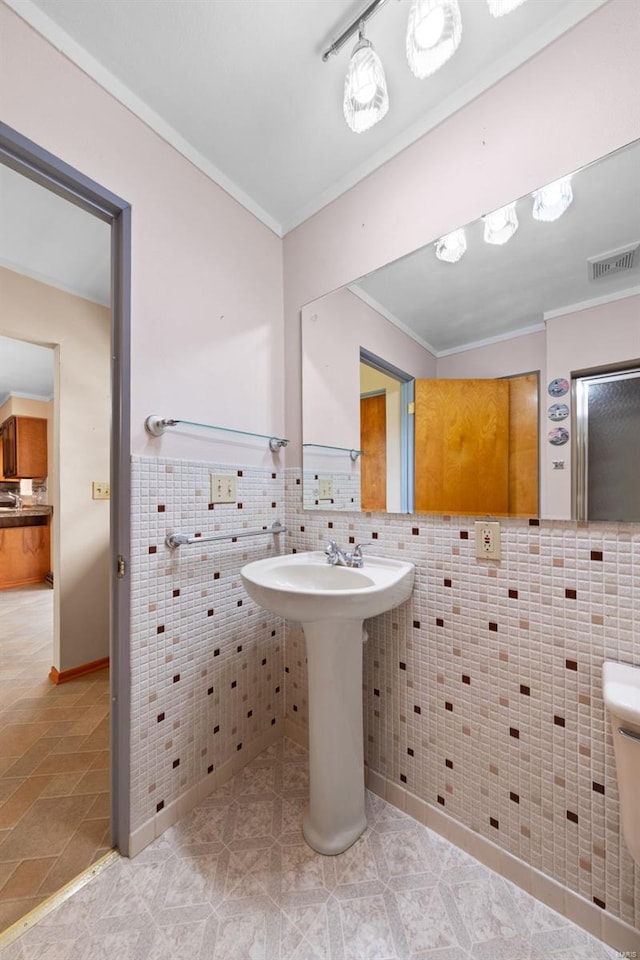 bathroom with tile walls, crown molding, a wainscoted wall, visible vents, and tile patterned flooring