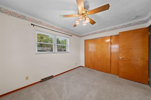 unfurnished bedroom with visible vents, a closet, baseboards, light carpet, and a ceiling fan