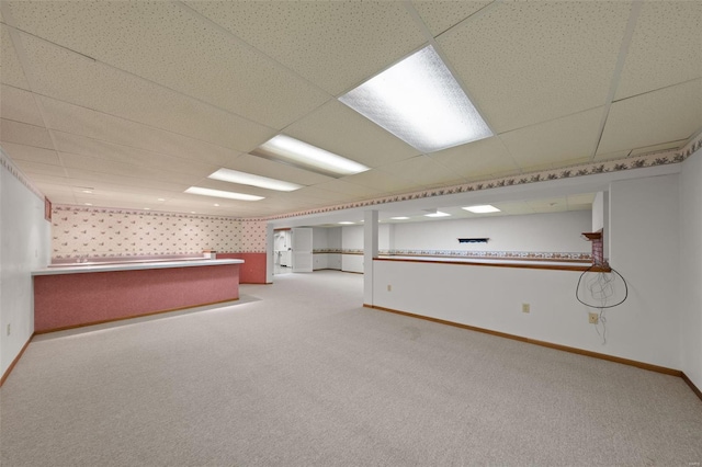 empty room featuring a paneled ceiling, carpet, and baseboards
