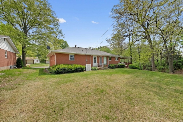 rear view of house featuring a lawn and brick siding