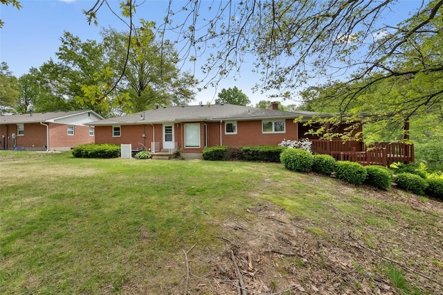 back of house featuring a chimney, central AC unit, a deck, and a lawn