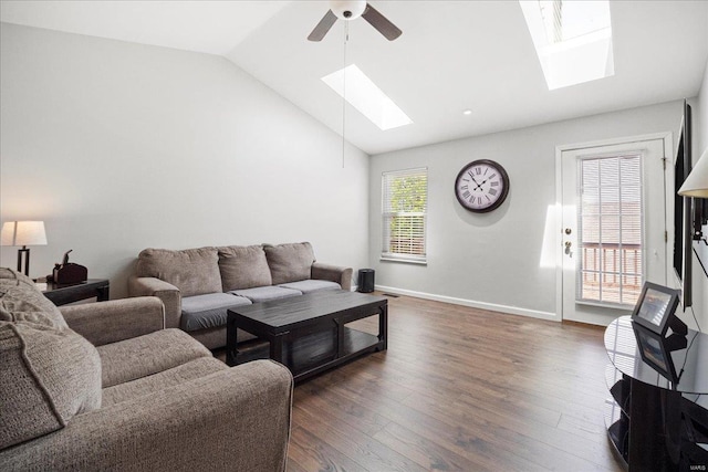 living area featuring baseboards, lofted ceiling with skylight, dark wood-style floors, and ceiling fan