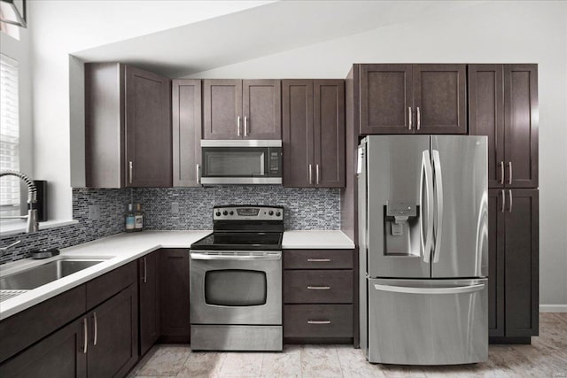 kitchen featuring dark brown cabinets, stainless steel appliances, backsplash, and lofted ceiling