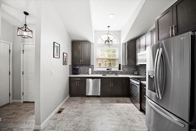 kitchen with light countertops, a sink, decorative backsplash, hanging light fixtures, and appliances with stainless steel finishes