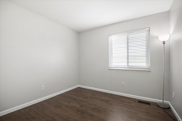 spare room with visible vents, baseboards, and dark wood-style flooring