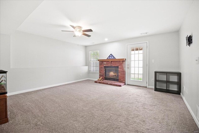 unfurnished living room with carpet, ceiling fan, a fireplace, baseboards, and visible vents