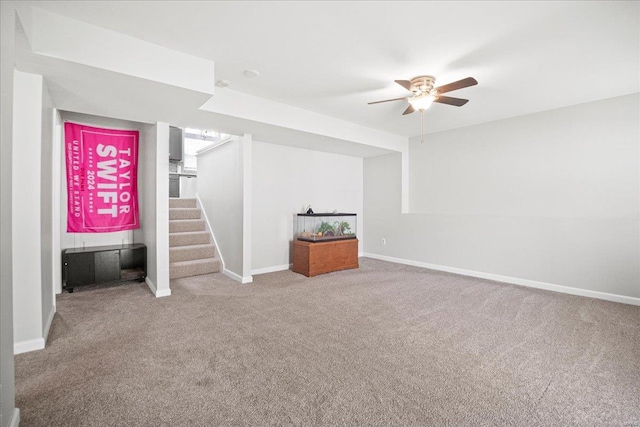 finished basement with baseboards, carpet flooring, stairs, and a ceiling fan