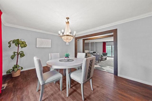 dining space featuring wood finished floors, a chandelier, ornamental molding, and baseboards