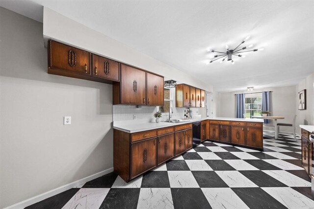 kitchen featuring decorative backsplash, a sink, light countertops, black dishwasher, and a peninsula