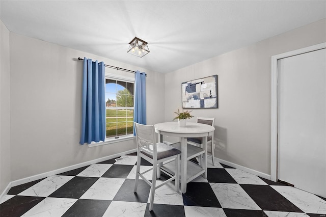 dining space with an inviting chandelier, marble finish floor, and baseboards