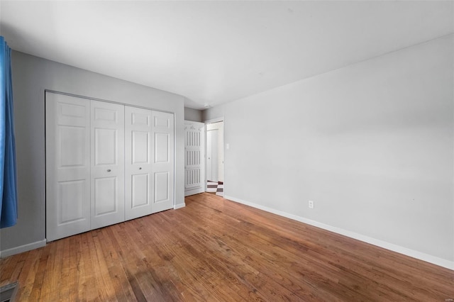unfurnished bedroom featuring a closet, wood finished floors, and baseboards