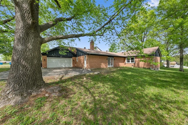 rear view of house with a chimney, brick siding, a lawn, french doors, and an attached garage