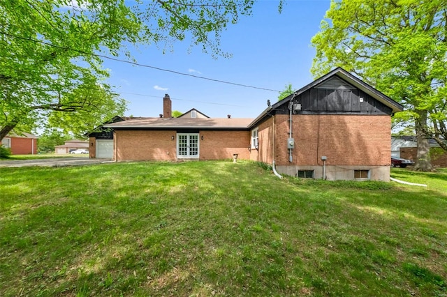 rear view of house with a lawn, a chimney, a garage, and brick siding