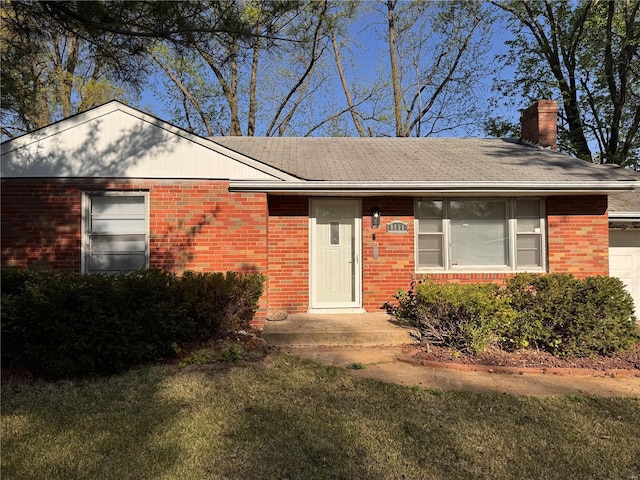 ranch-style house with a chimney, a shingled roof, brick siding, a front lawn, and a garage
