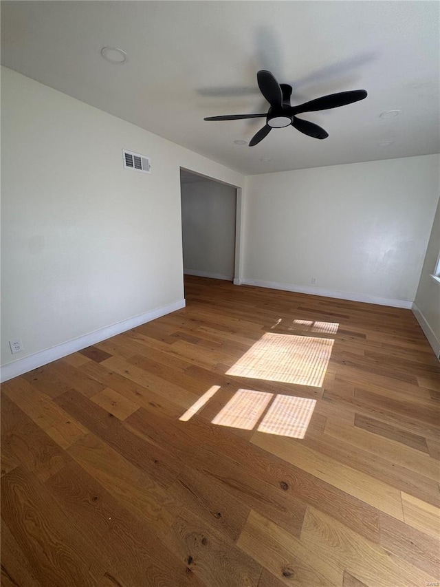 empty room featuring visible vents, ceiling fan, wood finished floors, and baseboards