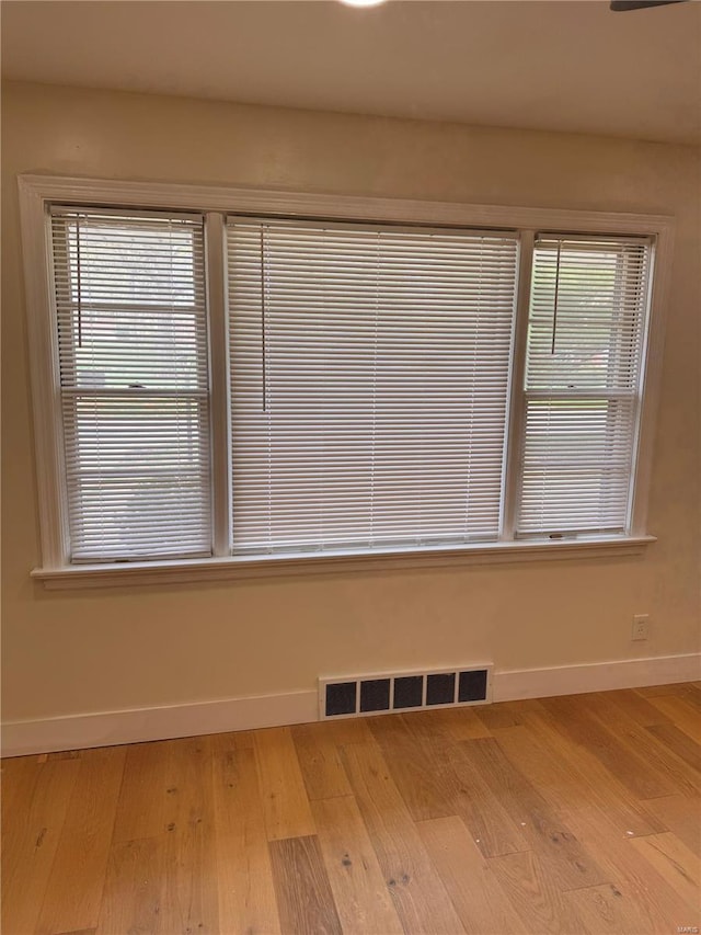 unfurnished room featuring wood finished floors, visible vents, and baseboards