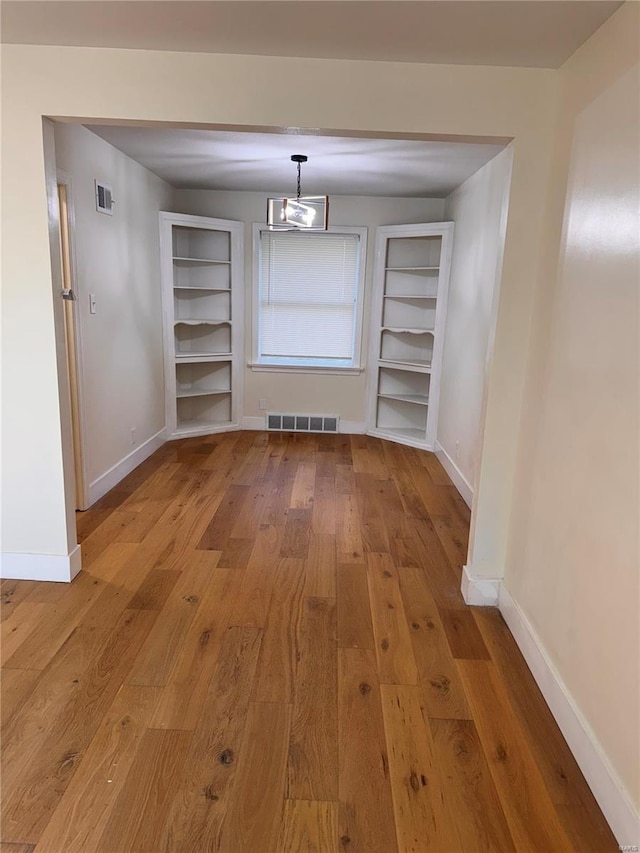 unfurnished dining area featuring wood finished floors, visible vents, and baseboards