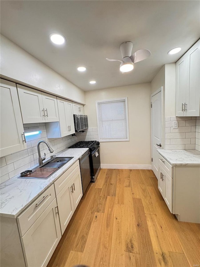 kitchen featuring light wood-style floors, backsplash, dishwasher, a sink, and baseboards