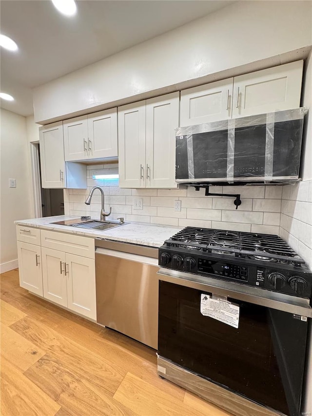 kitchen with a sink, dishwasher, backsplash, and gas stove