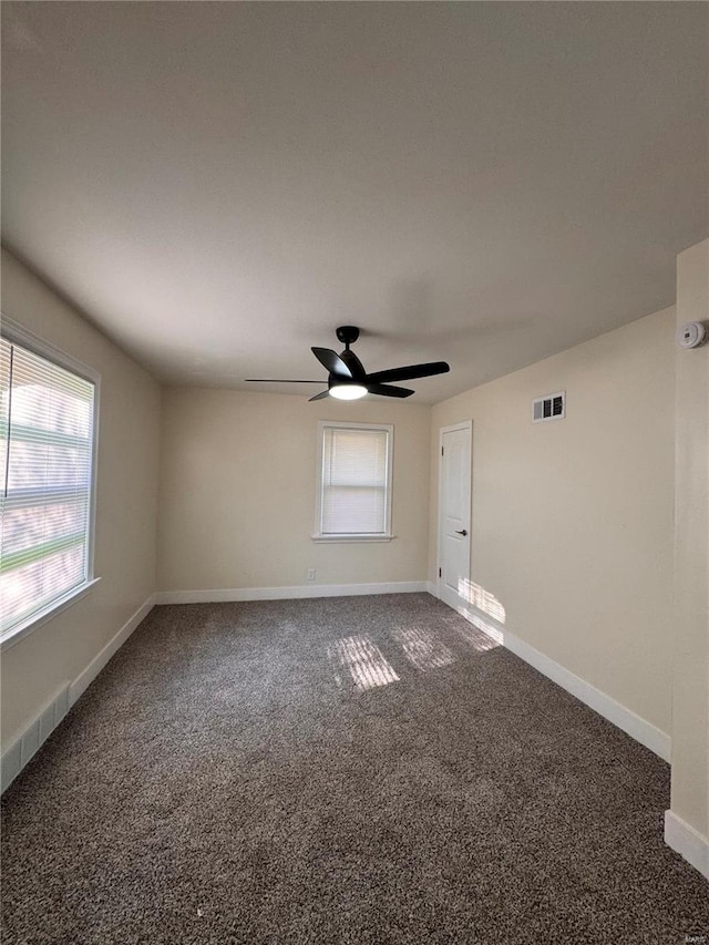 carpeted spare room with baseboards, visible vents, and ceiling fan