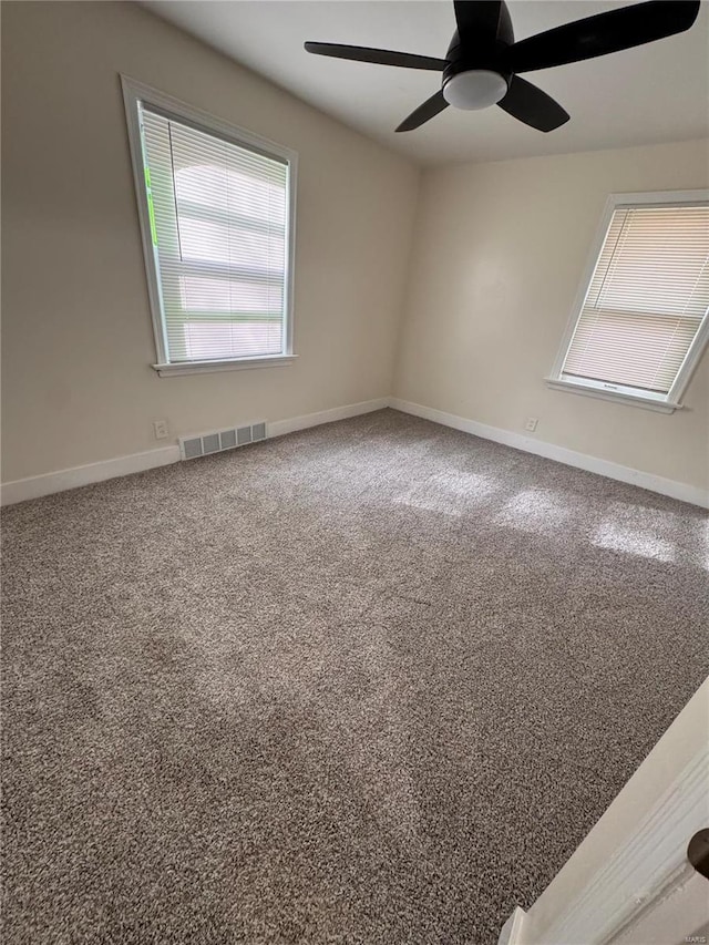 spare room with baseboards, visible vents, a ceiling fan, and carpet