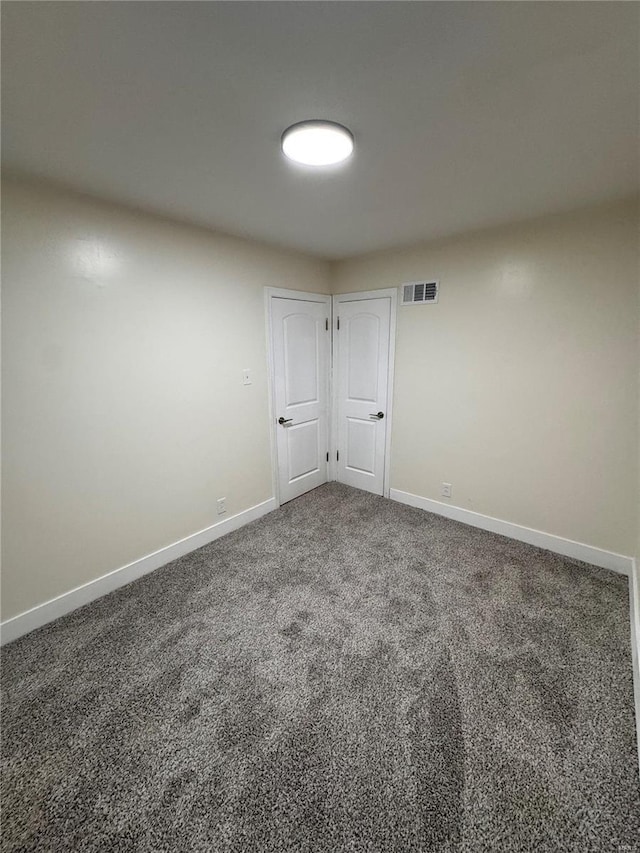 spare room featuring baseboards, visible vents, and carpet