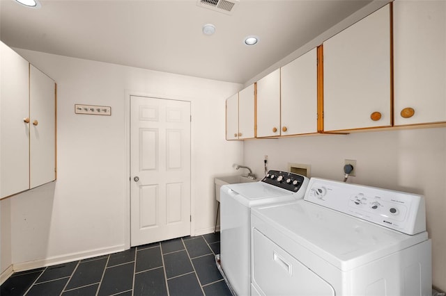 laundry area featuring dark tile patterned floors, visible vents, washing machine and dryer, cabinet space, and baseboards