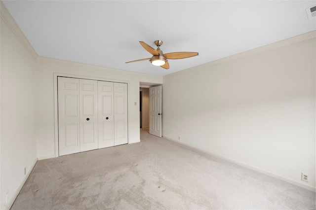 unfurnished bedroom with light colored carpet, baseboards, crown molding, and a closet