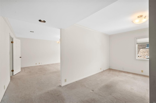 spare room featuring crown molding, carpet flooring, and baseboards