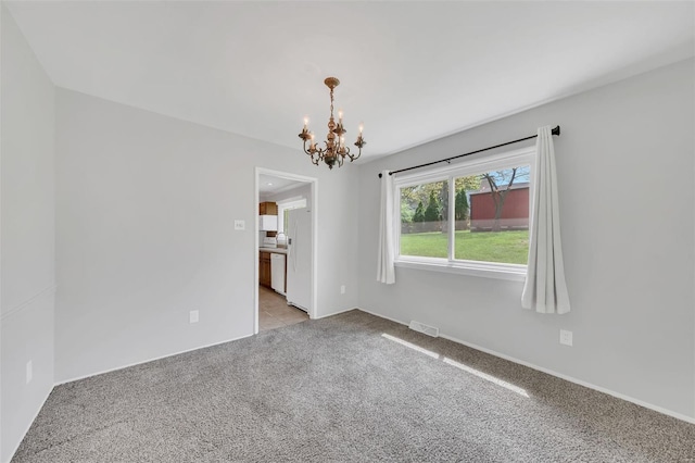 spare room with an inviting chandelier, visible vents, baseboards, and light carpet