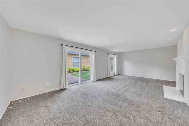 unfurnished living room with baseboards, visible vents, and carpet