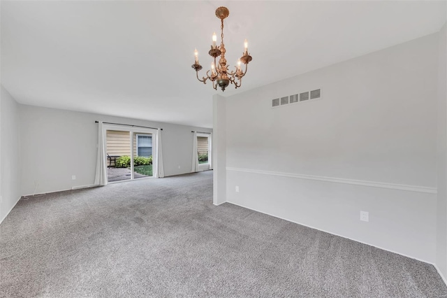 spare room featuring an inviting chandelier, visible vents, and carpet