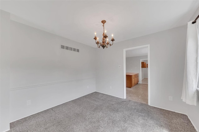 empty room with a chandelier, visible vents, and light colored carpet