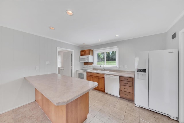 kitchen with light tile patterned floors, white appliances, a peninsula, light countertops, and ornamental molding