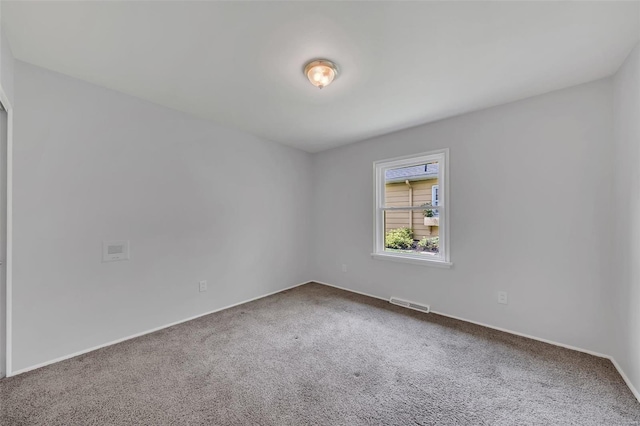 carpeted spare room featuring visible vents and baseboards