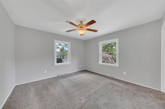 carpeted empty room with ceiling fan, visible vents, and a healthy amount of sunlight
