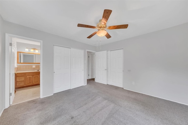 unfurnished bedroom featuring connected bathroom, a ceiling fan, two closets, and light carpet