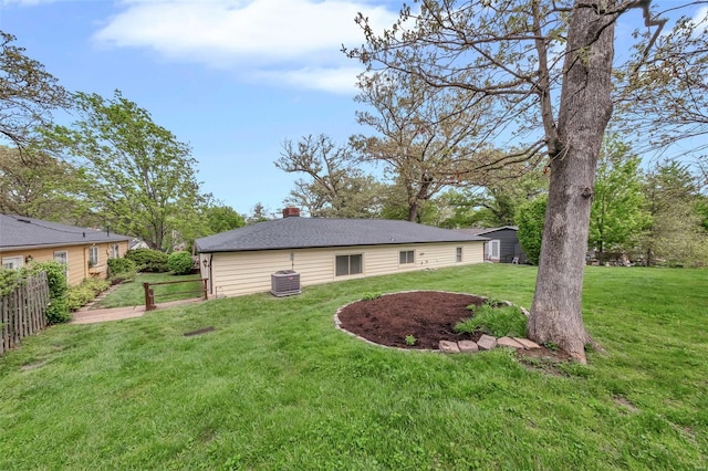 exterior space with fence, an outdoor structure, a chimney, a lawn, and central AC unit