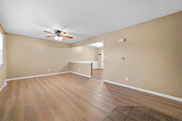 spare room with baseboards, a ceiling fan, and light wood-type flooring