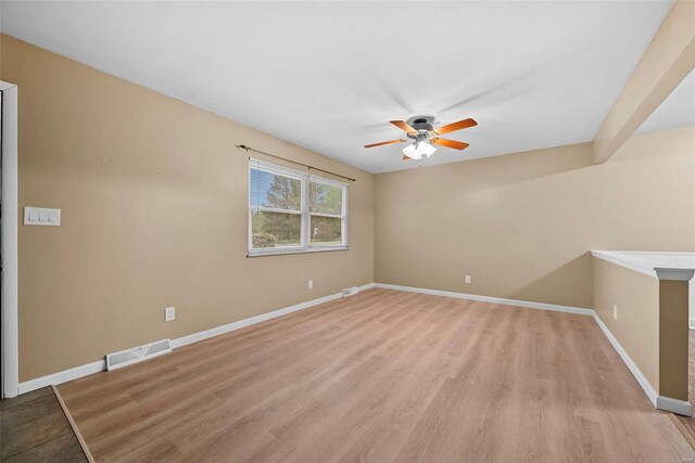 empty room with baseboards, ceiling fan, light wood-type flooring, and visible vents