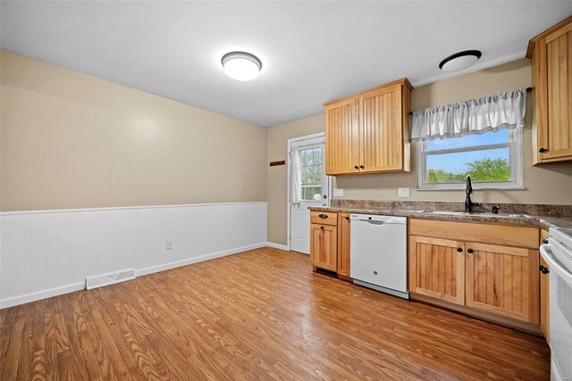 kitchen featuring visible vents, a sink, a wainscoted wall, light wood finished floors, and white appliances