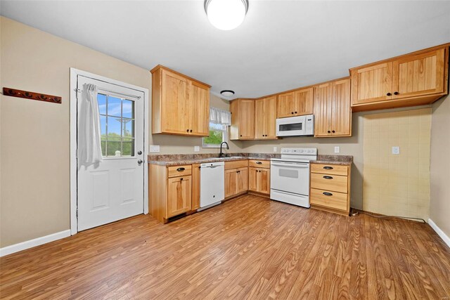 kitchen with light brown cabinetry, baseboards, white appliances, and light wood-style flooring